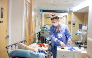 Nurse treating patient in emergency department hallway at MMC